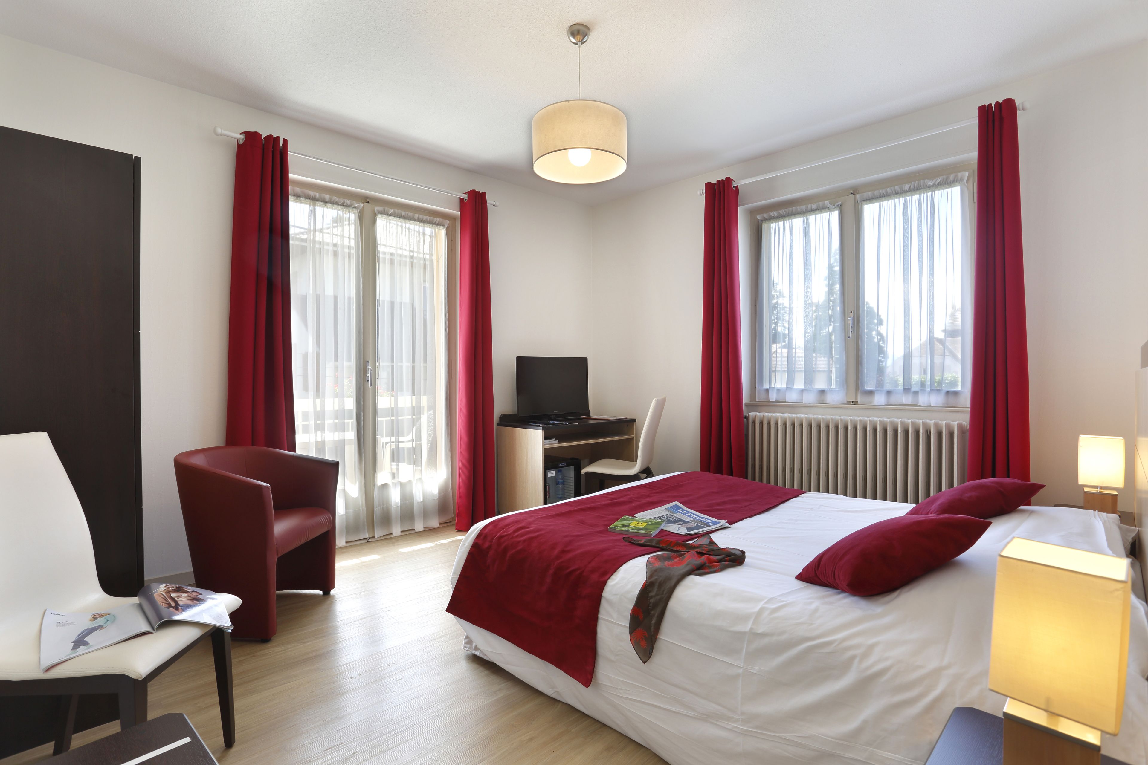 A hotel room with a bed, a desk, a chair, and a TV.