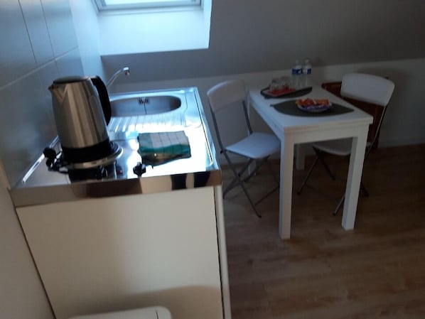 A small kitchenette with a sink, a kettle, and a table with chairs. - Chalet de Malvoue (Vimoutiers)
