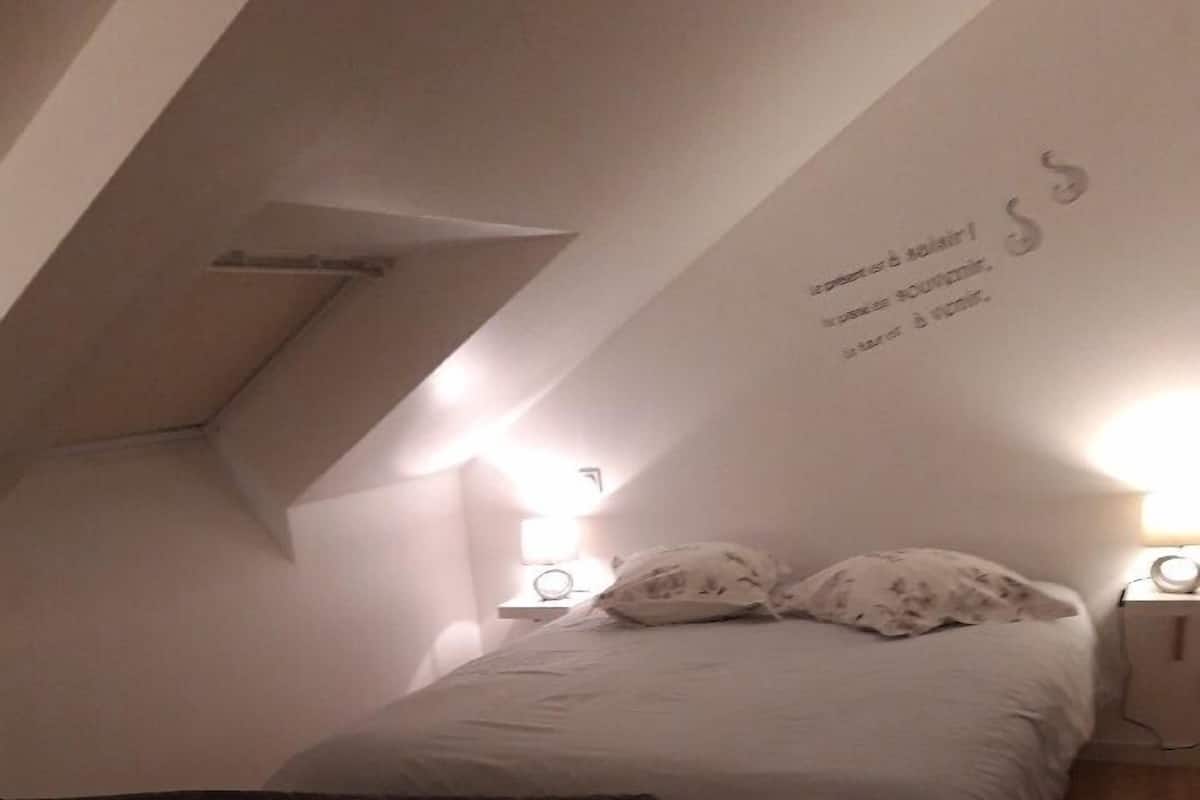 Een slaapkamer met een bed, een nachtkastje, een lamp en een bank.