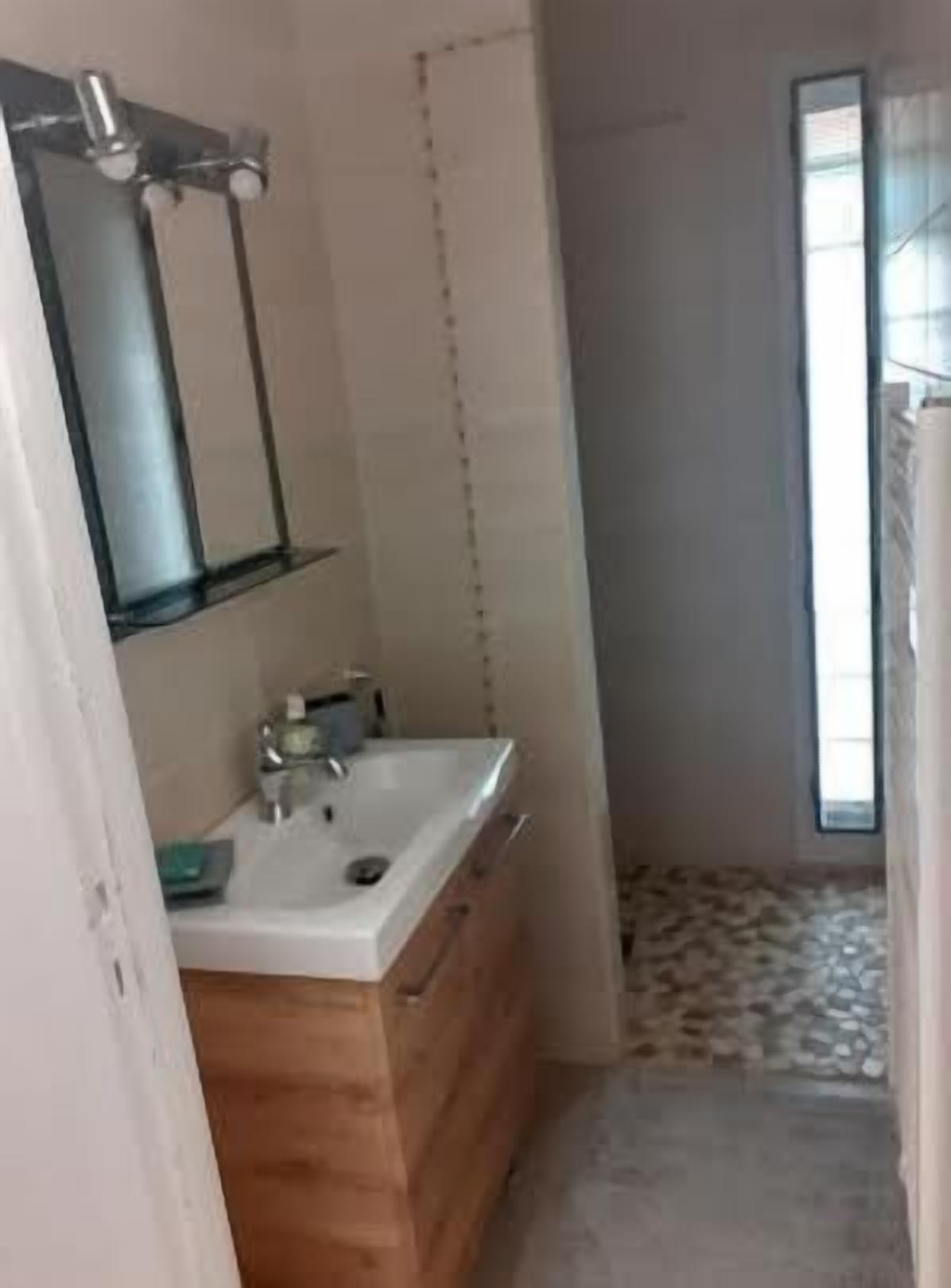 A bathroom with a wooden vanity, a white sink, and a mirror.