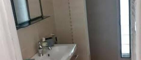A bathroom with a wooden vanity, a white sink, and a mirror.
