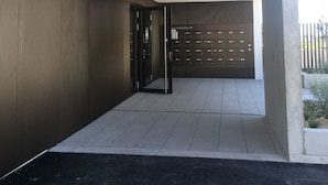 A modern building entrance with a metal gate, a tiled floor, and a concrete pillar.