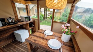 Une cuisine compacte équipée d’un four à micro-ondes, d’un grille-pain et d’un petit réfrigérateur. On y trouve une table à manger dressée avec des assiettes, des couverts et un vase de tulipes.