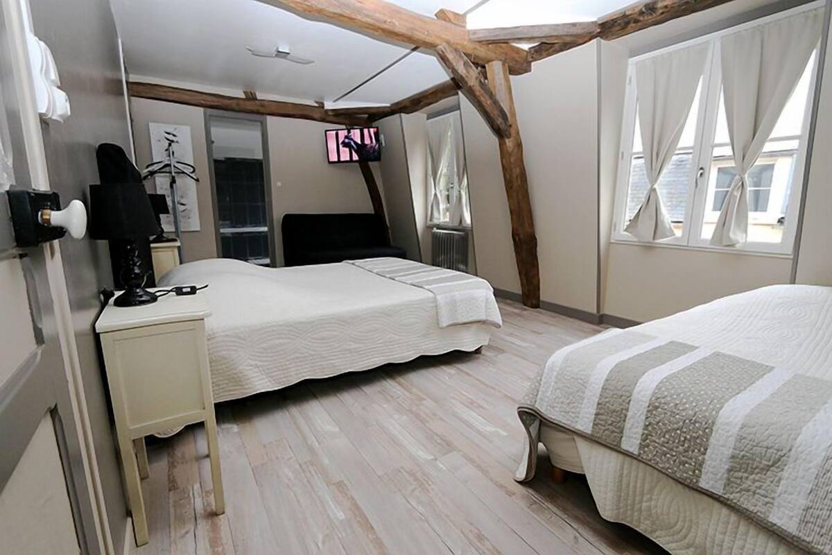 Un dormitorio con cama, escritorio, silla, televisión y ventana con cortinas.