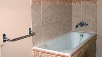 Un baño con bañera, toallero y azulejos decorativos.