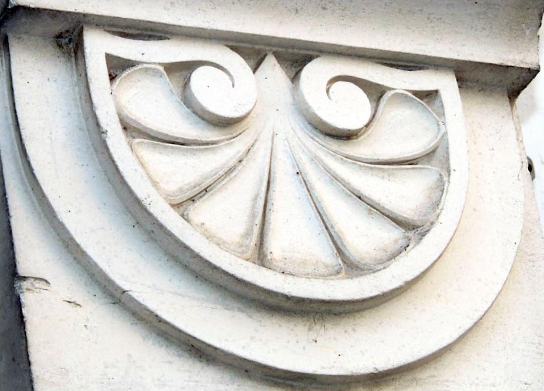 Detalle arquitectónico de piedra con diseño curvo y un motivo central similar a una hoja.