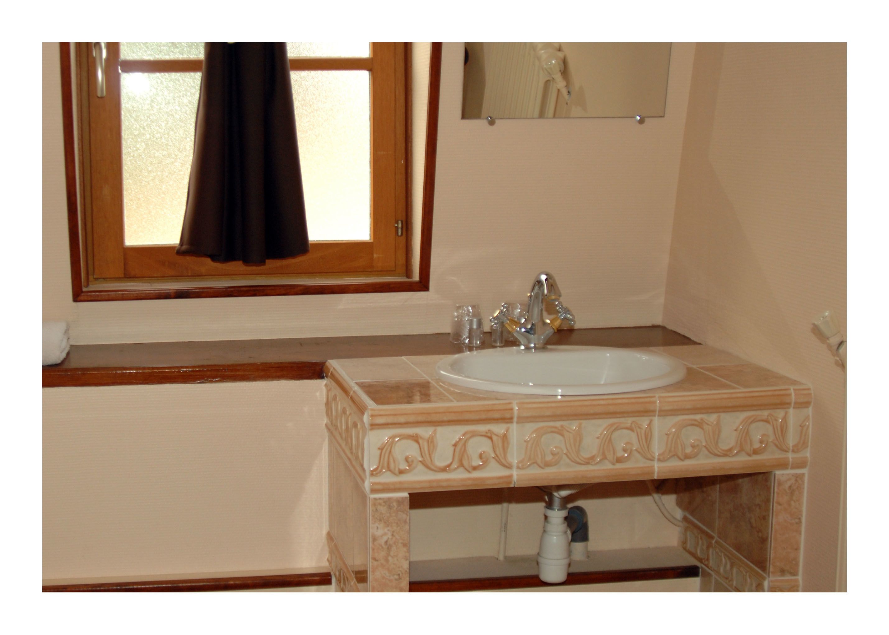 Baño con lavabo, espejo y ventana, con una toalla colgada.