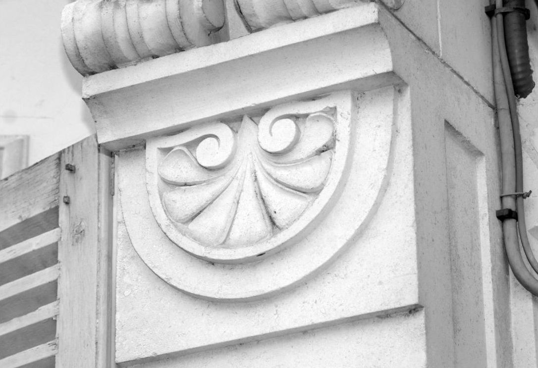 Un gros plan sur un détail architectural d’un bâtiment, mettant en valeur un élément décoratif en pierre sculptée, orné d’un motif en forme de coquille.