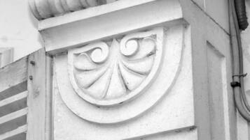Un gros plan sur un détail architectural d’un bâtiment, mettant en valeur un élément décoratif en pierre sculptée, orné d’un motif en forme de coquille.