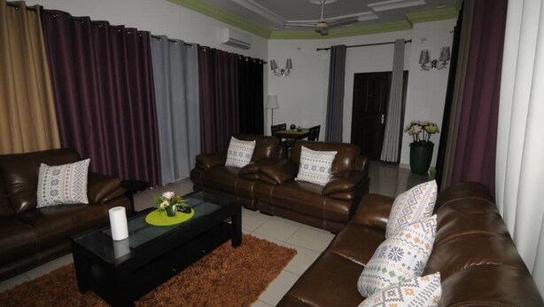 A living room with brown leather sofas, a black coffee table, and a brown rug. - Résidence Georges VI (Ouagadougou)