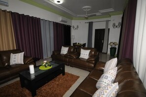 Una sala de estar con sofás de cuero marrón, una mesa de centro negra y una alfombra marrón.