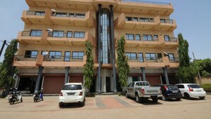 A multi-story building with a central column, balconies, and parked cars. - Résidence Georges VI (Ouagadougou)