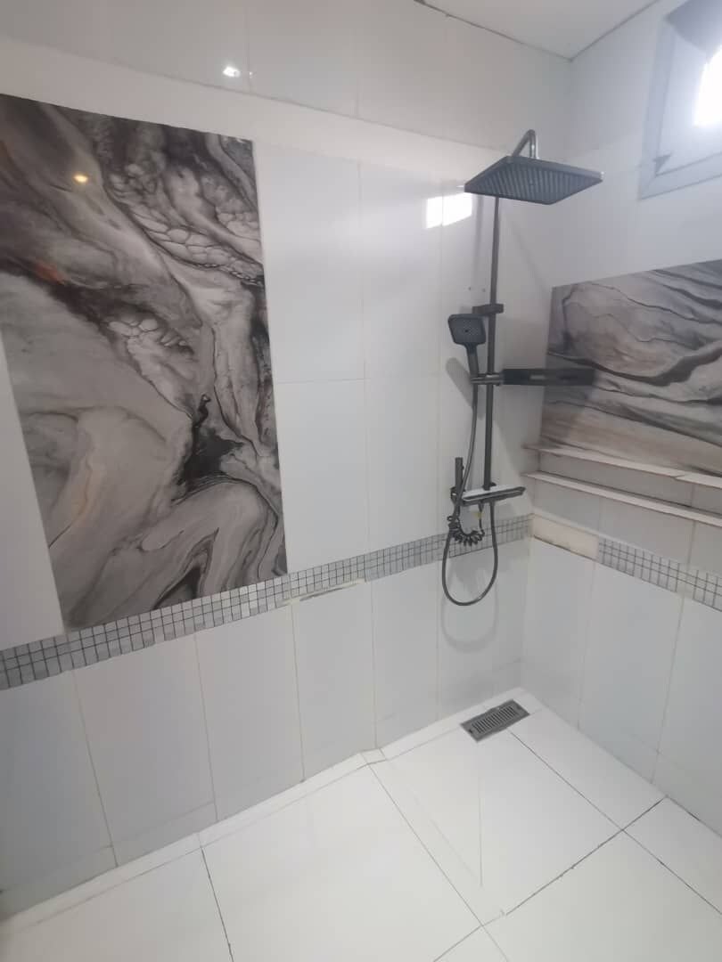 A bathroom with a shower, tiled walls, and a marble-like wall art piece.
