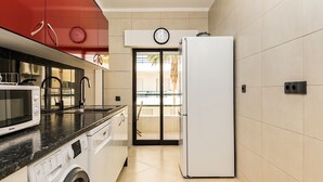 Eine kleine Küche mit Waschmaschine, Mikrowelle und Kühlschrank.