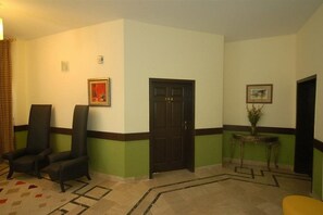 A lobby with two black armchairs, a door labeled 204, and a small table with a vase. - Hotel One Jinnah (Islamabad)