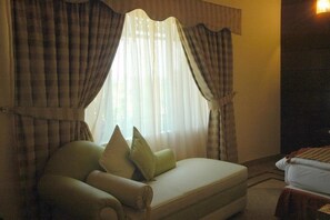 A room with a bed, a sofa, and a window with curtains. - Hotel One Jinnah (Islamabad)