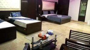 Une chambre d’hôtel avec deux lits, une table basse en verre, une chaise et un ventilateur de plafond.