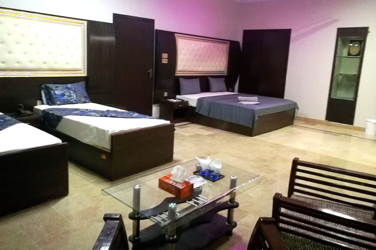 A hotel room with two beds, a glass coffee table, a chair, and a ceiling fan.
