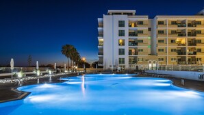 A swimming pool with a modern building in the background. - Hotel Apartamentos Dunamar (Vila Real Santo Antonio)