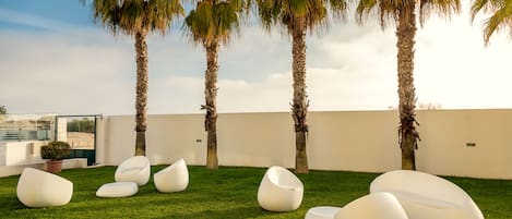A rooftop garden with palm trees and modern white seating.