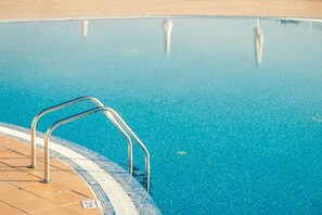 A swimming pool with metal handrails and a tiled edge. - Hotel Apartamentos Dunamar (Vila Real Santo Antonio)