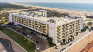 A multi-story hotel with a rooftop pool, a parking lot, and a view of the beach. - Hotel Apartamentos Dunamar (Vila Real Santo Antonio)