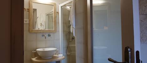 Un baño con lavamanos blanco, espejo y cabina de ducha.