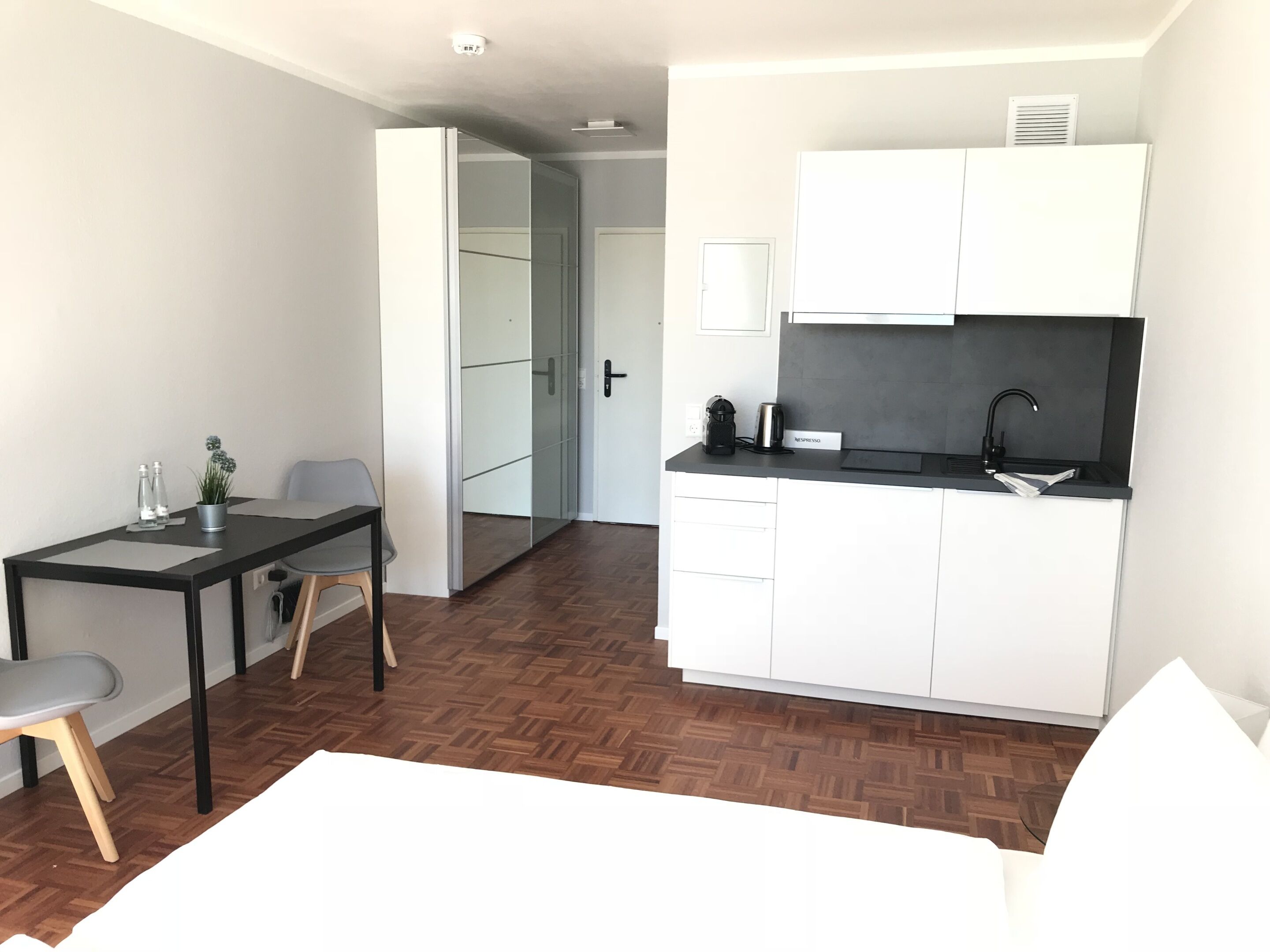 A compact living space with a kitchenette, a dining area, and a separate entrance.