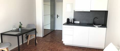 A compact living space with a kitchenette, a dining area, and a separate entrance.