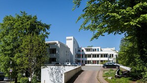 A modern building with a paved driveway leading to a parking area. - Hometown-Apartments (Heidelberg)