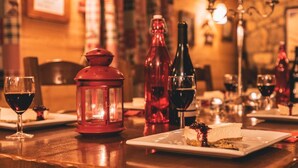 A restaurant setting with tables set for dining, wine glasses, and bottles of wine. - Chalet Cœur des Brévières by Chalet Chardons (Tignes)
