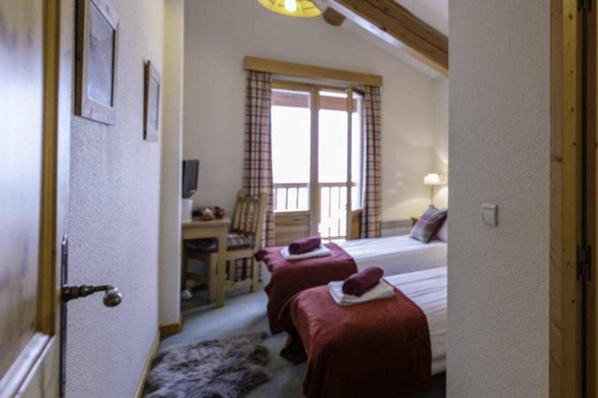 Une chambre avec deux lits, un bureau et un grand miroir.