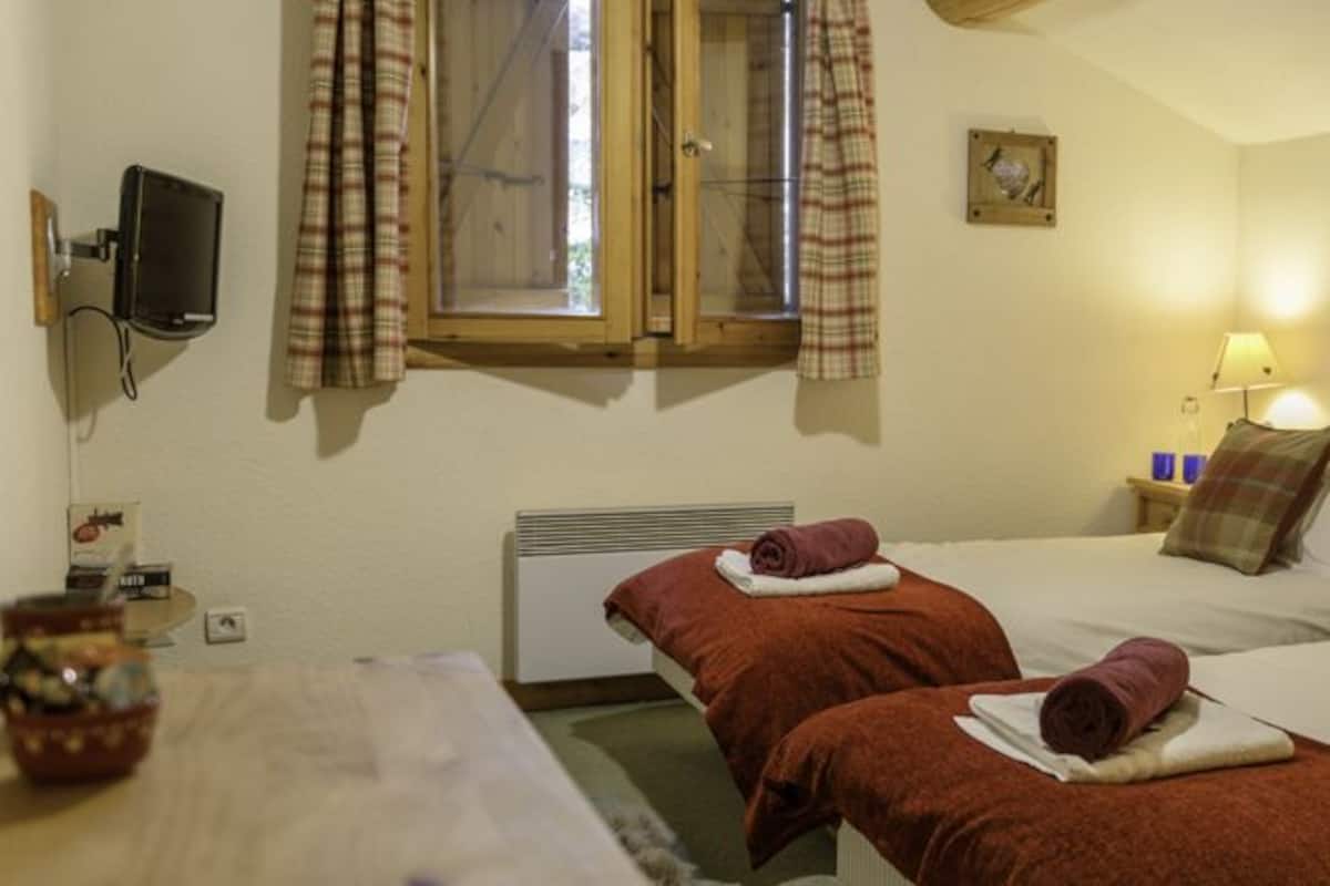 Une chambre d’hôtel avec deux lits, une tête de lit en bois, une table de chevet avec une lampe et un tableau au mur.