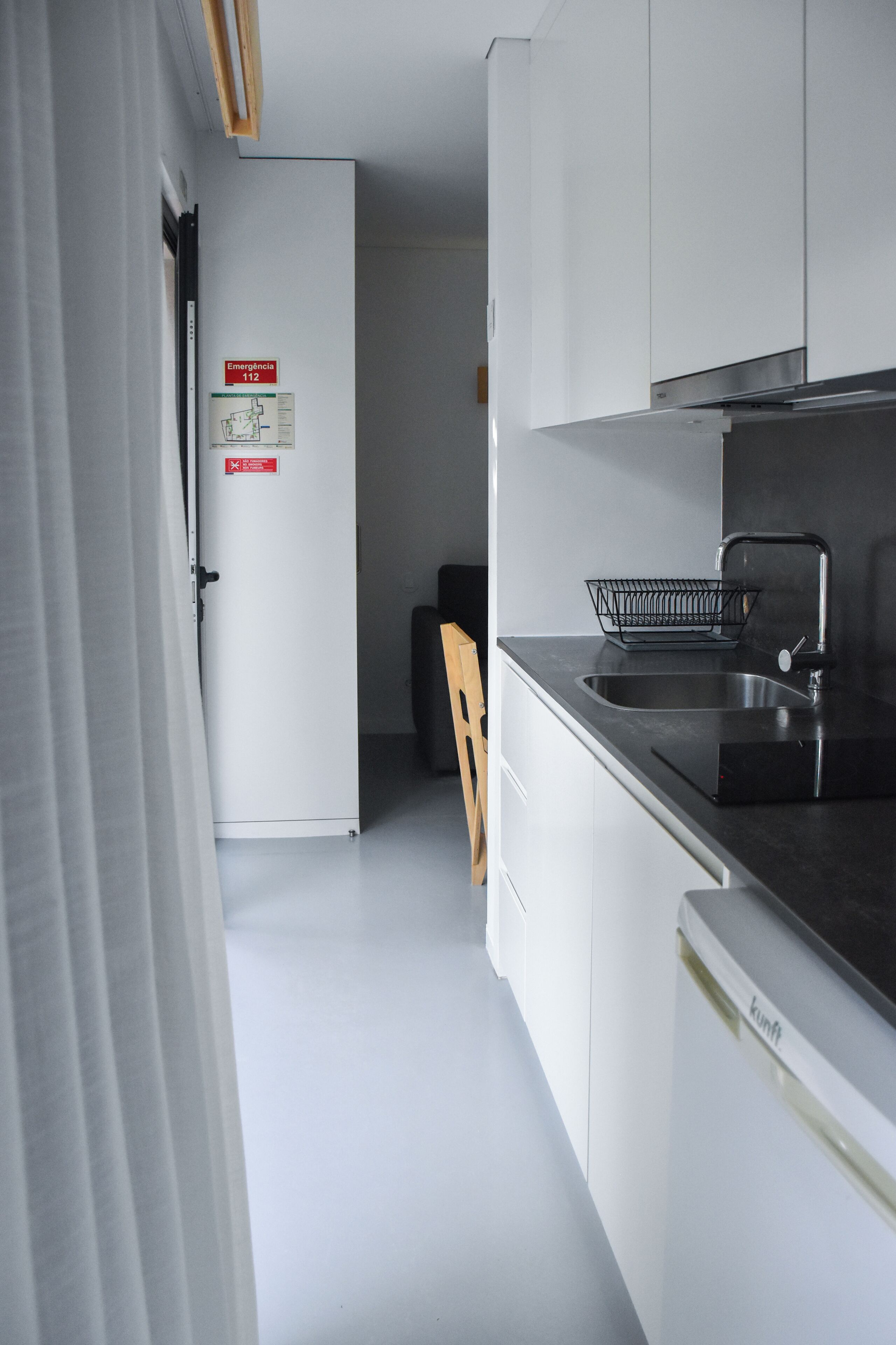 A modern kitchen with white cabinets, a black countertop, and a stainless steel sink.