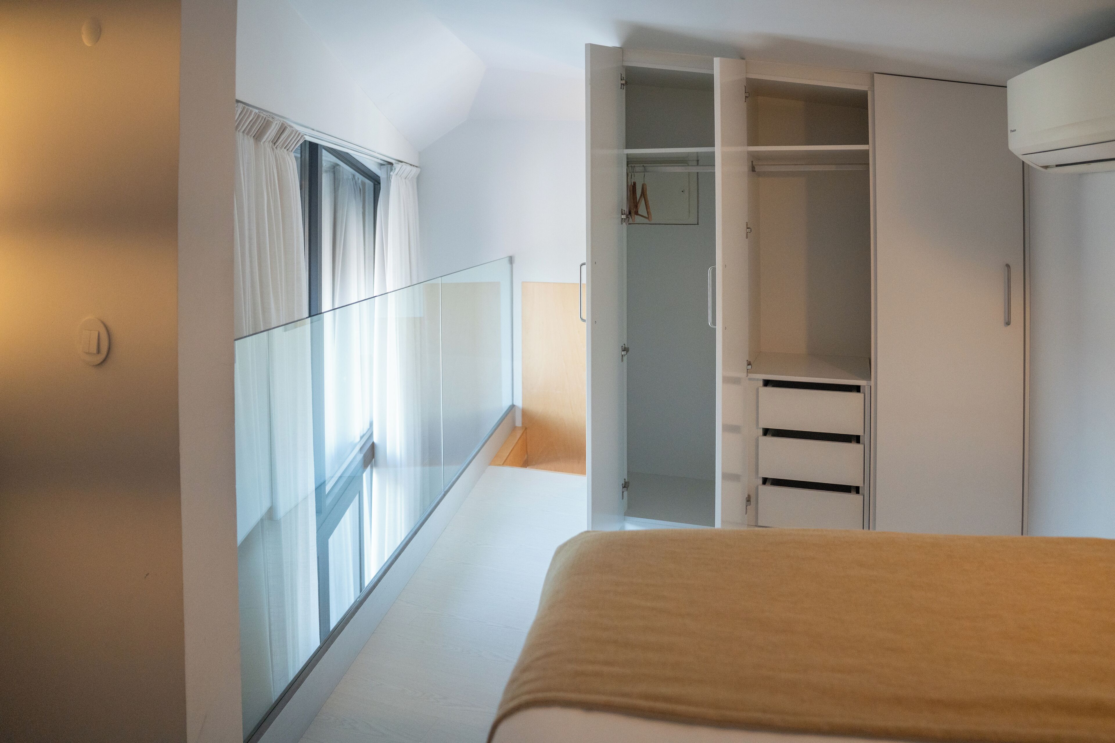 A bedroom with a bed, a closet, and a window with curtains.