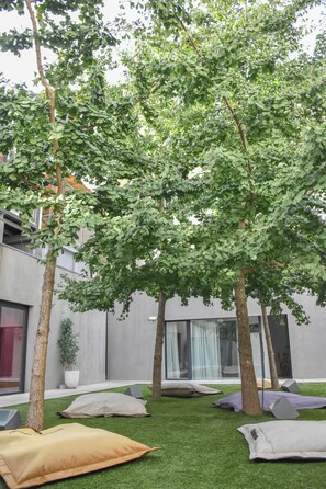 A courtyard with artificial grass, trees, and modern buildings in the background. - I Loft Porto (Porto)