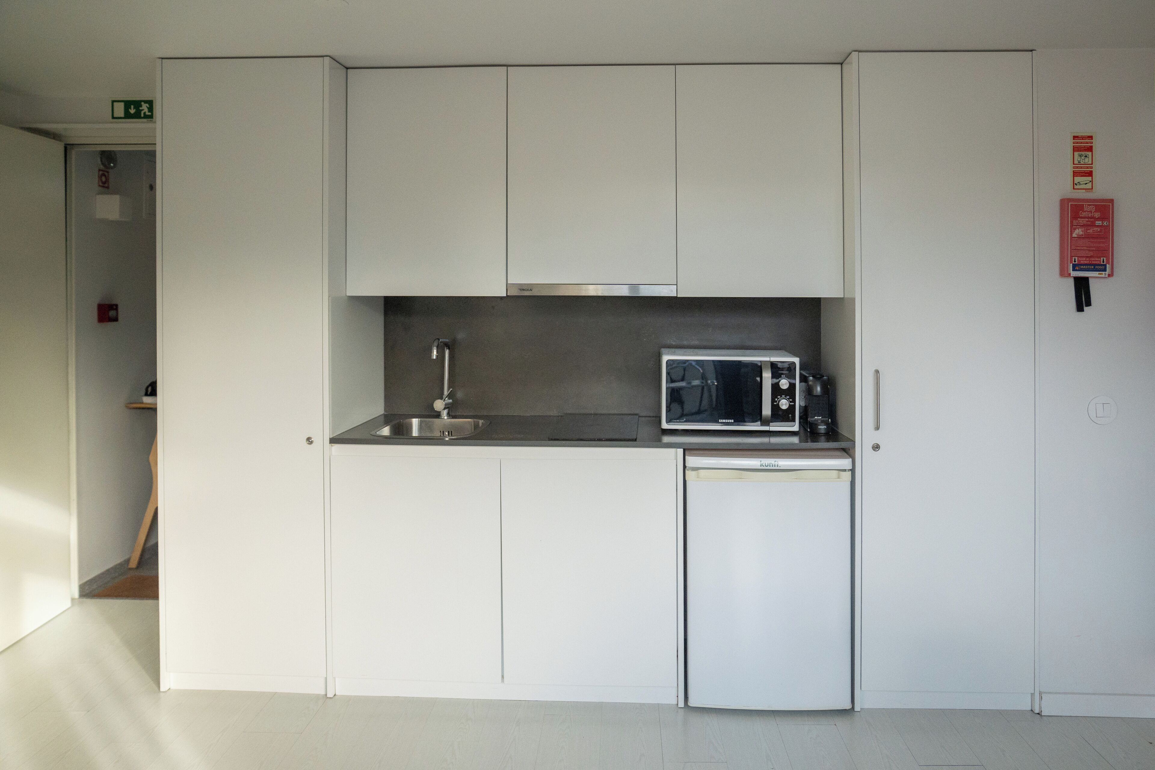 A compact kitchen with white cabinets, a microwave, a sink, and a dishwasher.