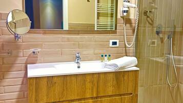 Une salle de bain avec un miroir, un lavabo, une serviette et un espace douche.