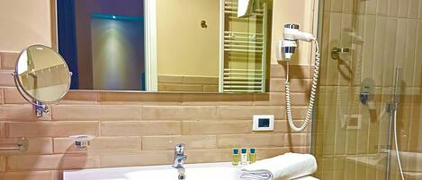 Une salle de bain avec un miroir, un lavabo, une serviette et un espace douche.