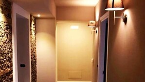 A hallway with wooden flooring, a stone accent wall, and wall-mounted lamps. - Home 146 (Lamezia Terme)