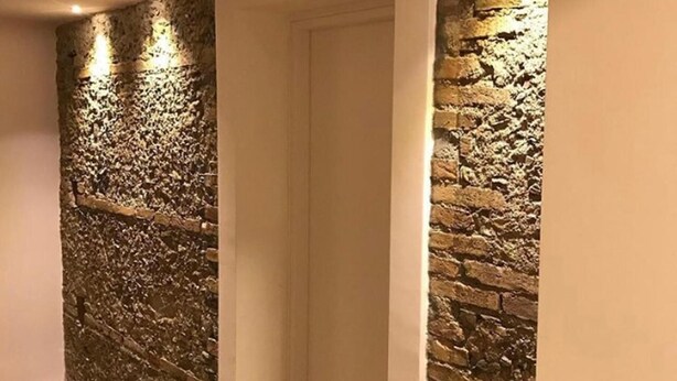 A hallway with a textured stone wall on one side and a plain white door on the other. - Home 146 (Lamezia Terme)