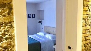 A narrow hallway leading to a bedroom with a bed, a nightstand, and a wall-mounted lamp. - Home 146 (Lamezia Terme)