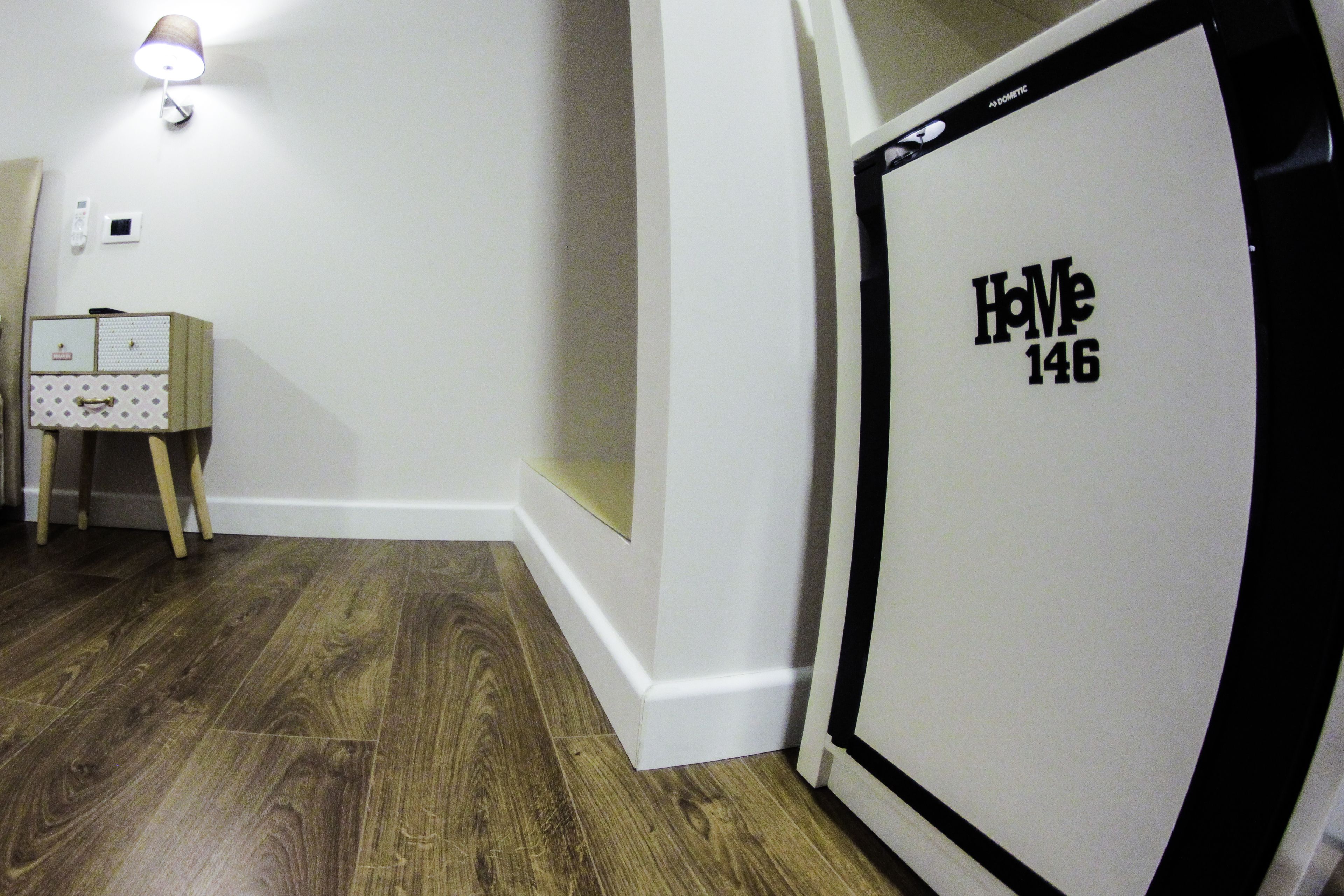 Ein Flur mit Holzboden, weißer Wand und einer Tür mit der Aufschrift 'Home 146'.