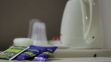 A white electric kettle and two packets of tea on a white countertop.