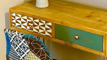 A wooden desk with a patterned drawer and a vase with flowers.