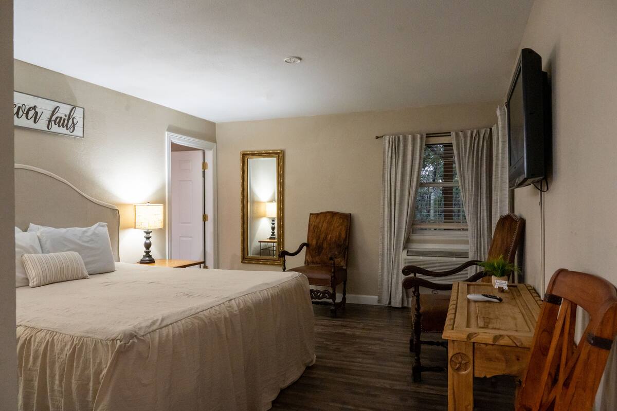 Ein Hotelzimmer mit Bett, Schreibtisch, Sessel, Fernseher und Spiegel.