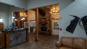 A spacious living area with a stone fireplace, wooden beams, and a leather sofa.