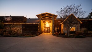 A rustic lodge entrance with a wooden facade, a stone wall, and a welcoming archway.