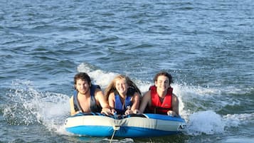 Three people on a blue and white inflatable raft in the water.