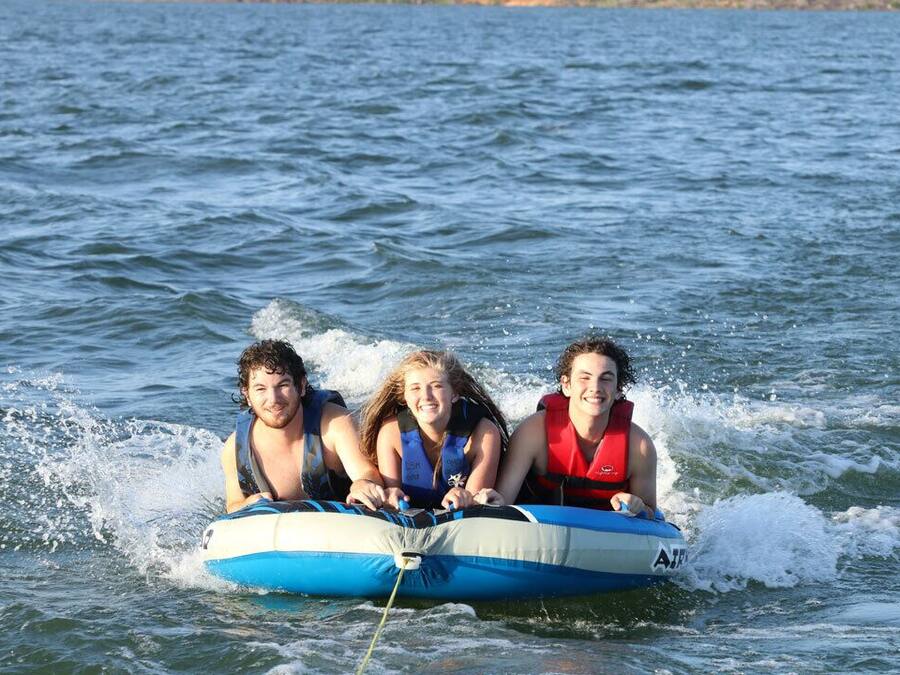 Three people on a blue and white inflatable raft in the water.